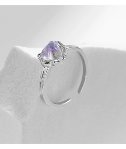 Macro shot of silver ring with irregular moonstone on white stone texture