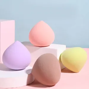 Four-piece peach makeup sponge set in pink, purple, and tan on geometric display stands