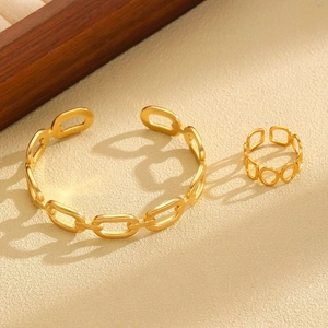 Polished gold jewelry set with hollow ring and chain link bracelet on textured background