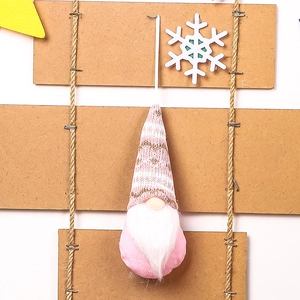 Detailed close-up of pink and white knitted Christmas gnome ornament with plush beard