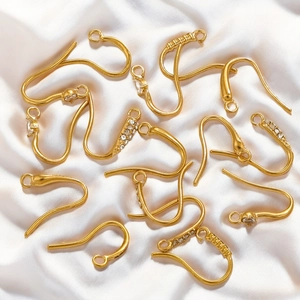 Golden stainless steel earring hooks in plain and rhinestone styles on white silk