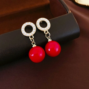 Vintage geometric gold hoop earrings with white pearls and red beads on brown silk background