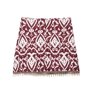 Detail eines Minirocks mit Ikat-Print in Burgund und bunten Perlenfransen am Saum