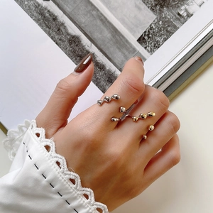 Irregular liquid lava style gold and silver rings worn against a lace cuff background