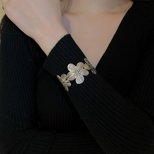 Detail of vintage flower cuff bracelet with brushed petal texture on black sweater