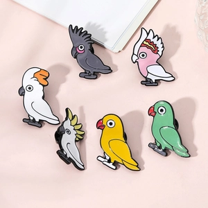 Détail de six broches perroquet colorées en émail sur un fond rose pastel élégant