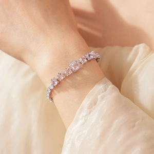 Close-up of sparkling pink zircon silver chain bracelet worn on wrist with elegant drapes