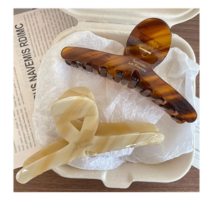 Macro view of tortoiseshell and marble acetate hair claws with gold Barrette La France text