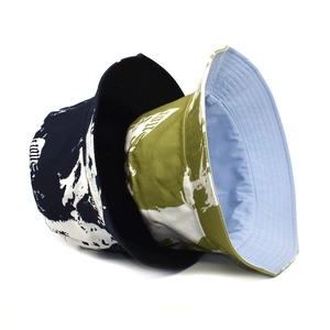 Vue détaillée de bobs en coton tie-dye bleu marine et vert olive avec motifs imprimés