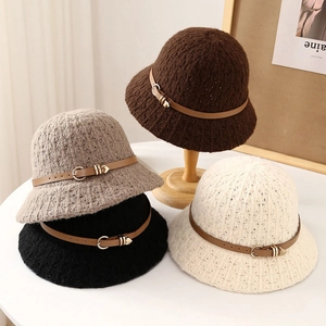 Knit bucket hat with leather strap decor in four colors shown on a wooden stand