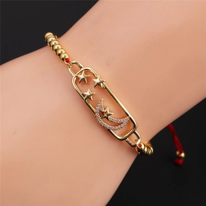 Detailed close-up of a gold star and moon bracelet with zircon charms on a black background