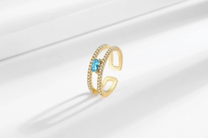 Detail of adjustable gold ring featuring a rectangular blue gem and micro-paved zircons