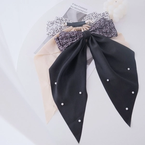 Detailed display of floral, black, and beige fabric bow hair clips with pearl accents