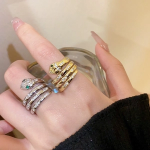 Close-up of gold and silver snake rings with cubic zirconia and green gem eyes