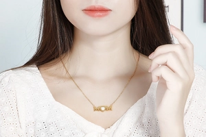 Detailed view of gold MOM heart pendant necklace worn on neck as a Mother's Day gift