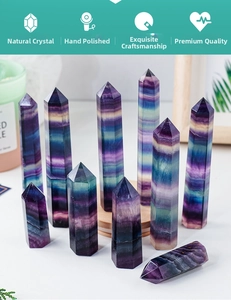 Polished natural rainbow fluorite hexagonal prisms in purple and blue tones on a white desk