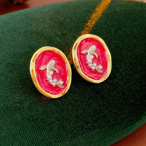 Detail of vintage goldfish earrings with red enamel and small pearls on green velvet