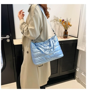 Blue metallic puffy tote bag shown as a crossbody bag with wide shoulder strap details