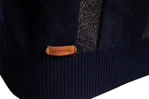 Détail d'un pull en maille marine montrant la texture fine et l'écusson en cuir