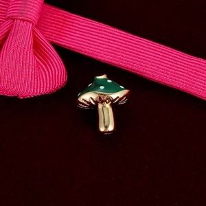 Macro detail of a cute green mushroom charm with white dots on red velvet background