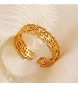 Vue macro d'une bague géométrique dorée ajourée sur un tissu en soie élégant