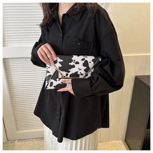 Detail of a cow print envelope clutch bag with metal trim and fold-over flap design