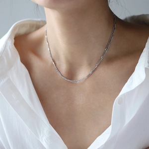 Détail d'un collier multi-rangs en acier titane argenté avec des breloques hirondelles sur un mannequin