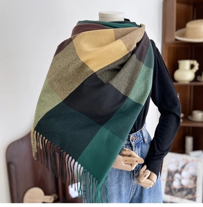 Detail of dark green and brown checkered scarf with long fringe on a mannequin