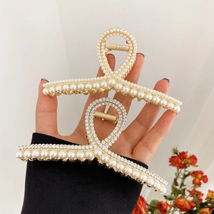 Pinces à cheveux en métal doré avec perles et strass élégamment tenues en main