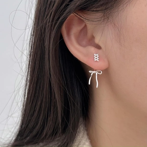 Detailed close-up of a 925 sterling silver bow earring on ear showing delicate metal texture