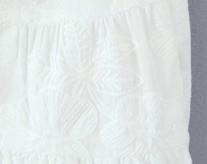Détails de broderie florale blanche délicate sur un tissu texturé de qualité