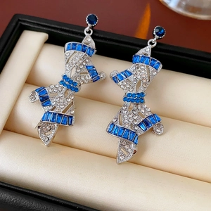 Detail of vintage silver bow earrings featuring blue and clear rhinestones in a jewelry box
