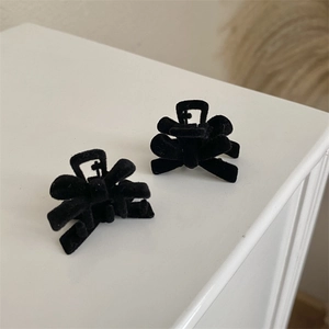 Close-up of two vintage black velvet bow hair clips with a premium flocked texture