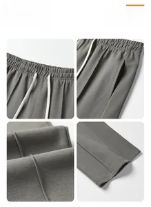 Detail view of grey casual trousers showing drawstring waist, side pockets, and fabric texture