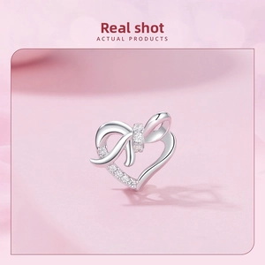 Detailed view of a silver heart charm with bow design and zircon stones for DIY bracelets