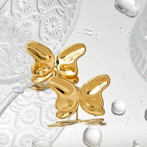 Polished 316 stainless steel butterfly stud earrings in gold on decorative glass