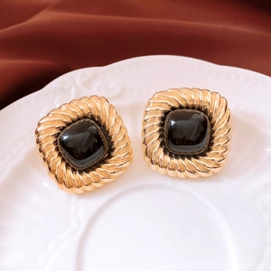 Close-up of vintage square gold earrings with black stone and twisted rope edge