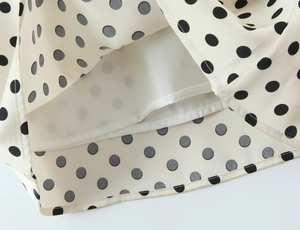 Détail du tissu en satin beige à pois avec des coutures soignées et une doublure blanche
