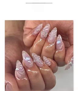 Detail of almond press-on nails with 3D butterfly, heart, and embossed floral designs