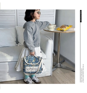 Close-up of kids floral crossbody bag in blue fabric with adjustable white strap