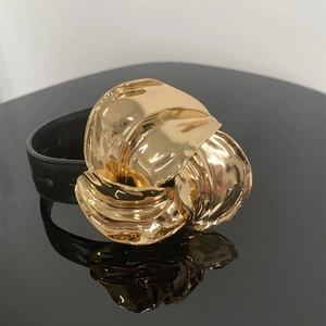 Gedetailleerde macro-opname van een zwarte leren armband met grote gouden metalen gesp