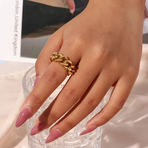 Close-up of golden cuban chain woven open ring worn on a model's finger with soft lighting