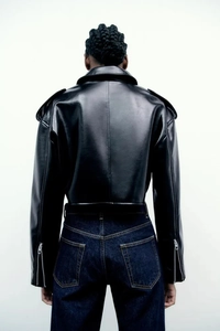 Back view of a cropped black PU leather jacket with shoulder straps and loose fit silhouette