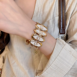 Detail of vintage gold-toned oval link bracelet with white enamel and Greek key motifs