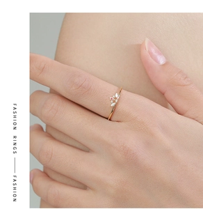 Close-up of gold crown ring with marquise pink and white stones on female finger