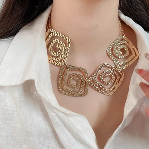Macro shot of gold hammered square links on a statement necklace worn by a model