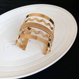 Detail of a multi-layer gold hollow wavy bangle placed on a white ceramic plate