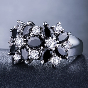 Dettaglio macro di un anello a fiore con pietre marquise nere e cristalli lucenti