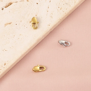 Detailed view of 18K gold plated and silver lobster clasps on a textured stone surface