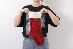Detail of hand opening a red knitted Christmas stocking with a white folded cuff